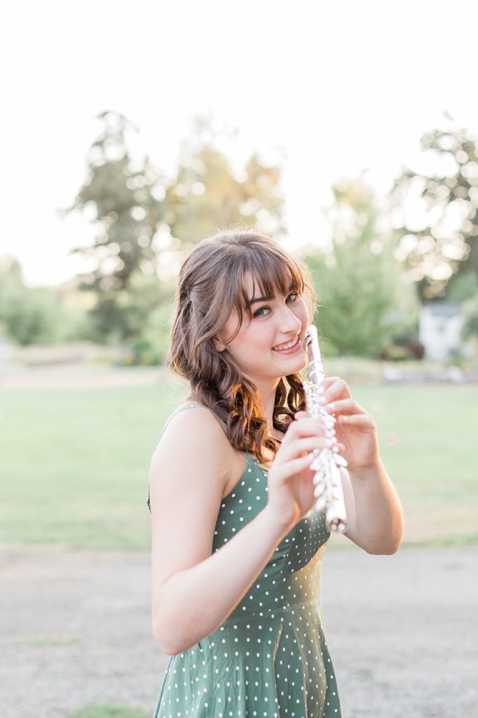 senior photos with girl in a field playing her flute in Eugene, Oregon