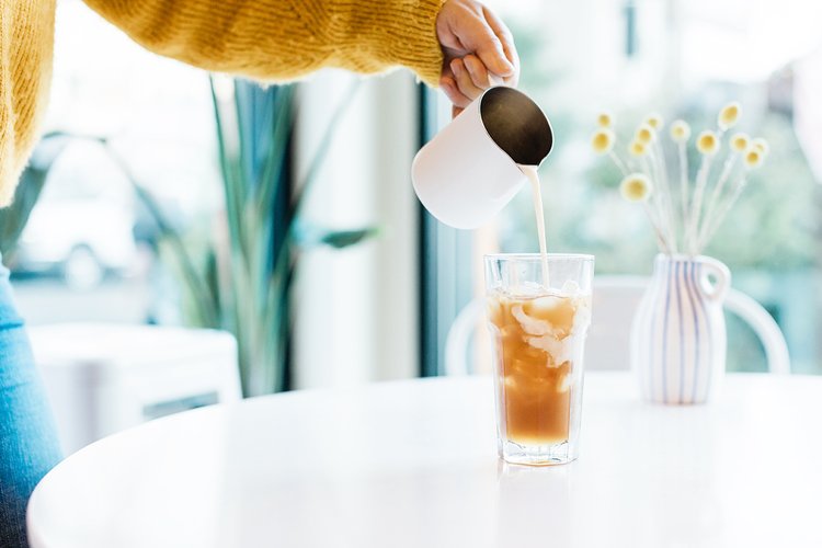branding product photoshoot with woman pouring cream into an iced coffee