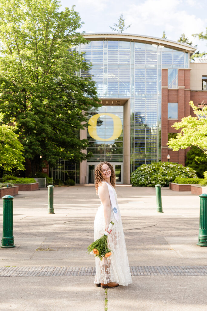 girl graduate graduation hat white dress trees buildings University of Oregon graduation photos in Eugene