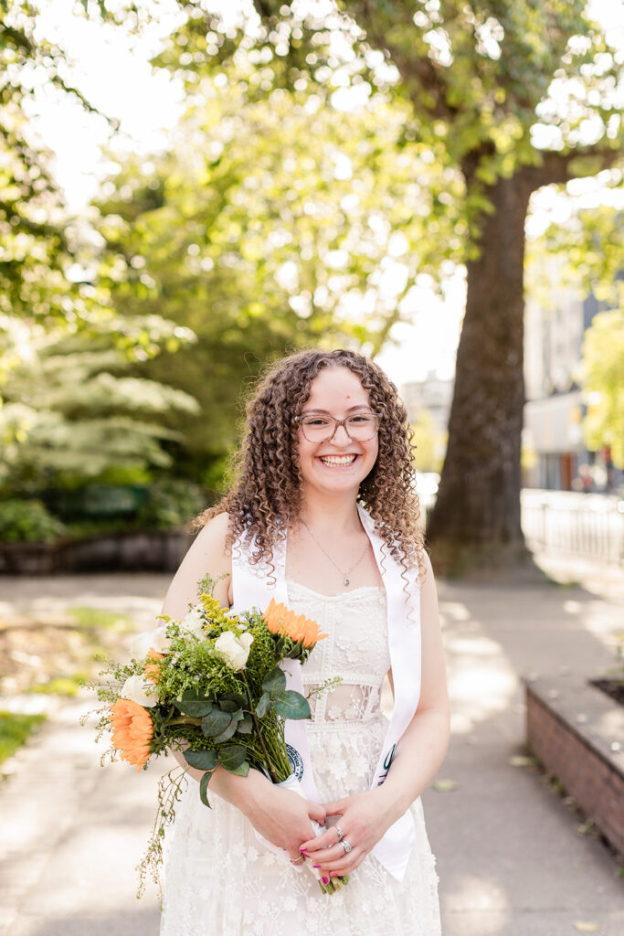 girl graduate graduation hat white dress trees buildings University of Oregon graduation photos in Eugene